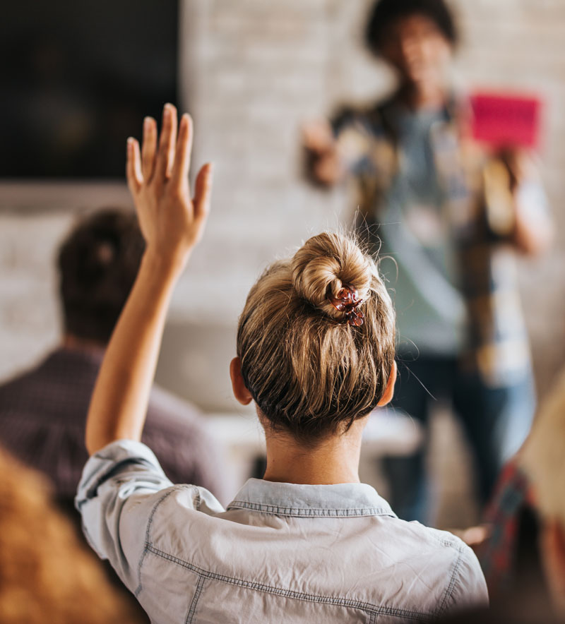 Women raising her hand and asking a question at a session